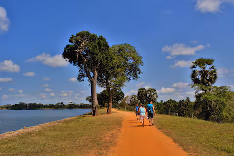 Guests walking a lakeside path under a blue sky